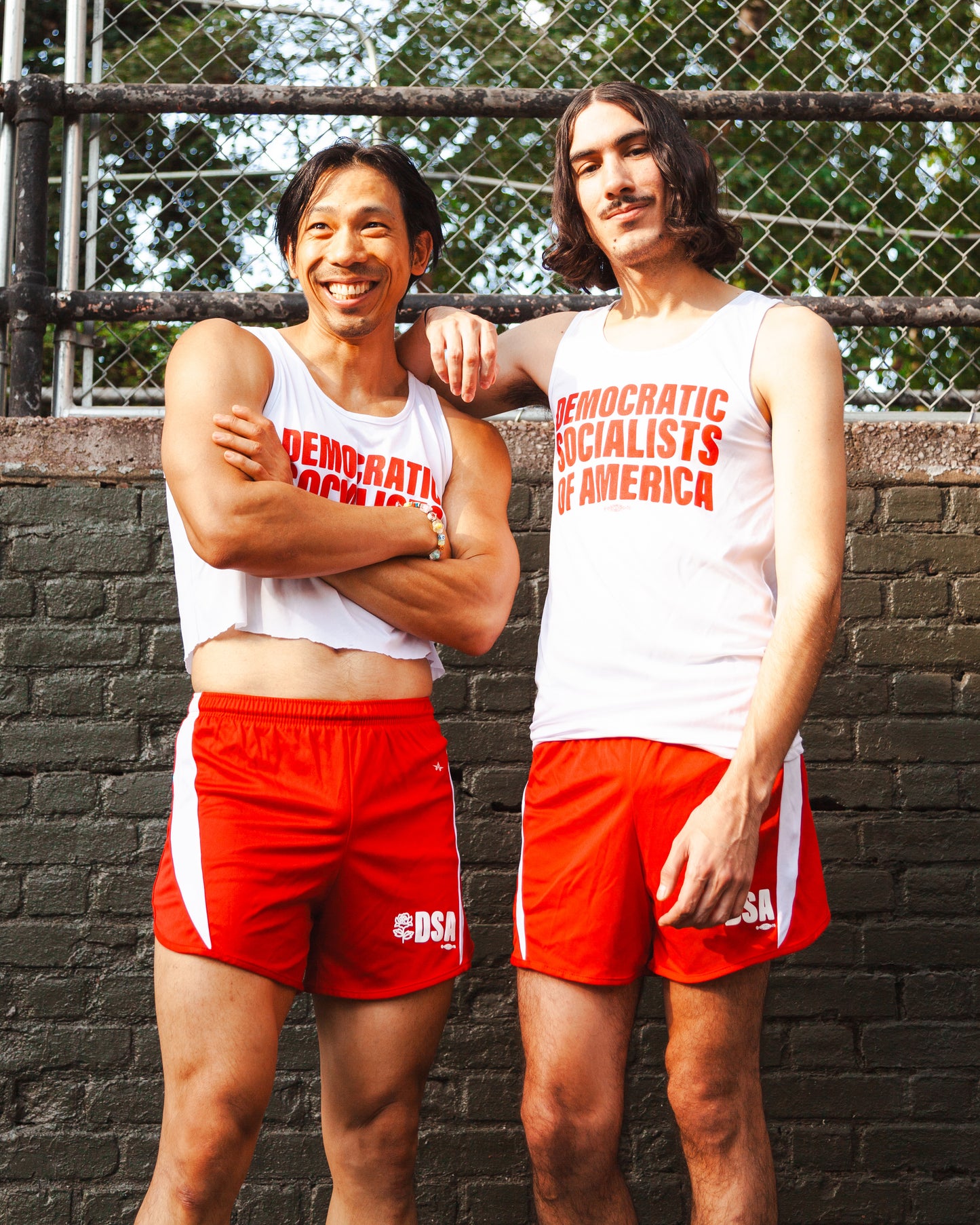 Two socialists in a public park wearing DEMOCRATIC SOCIALISTS OF AMERICA track uniforms