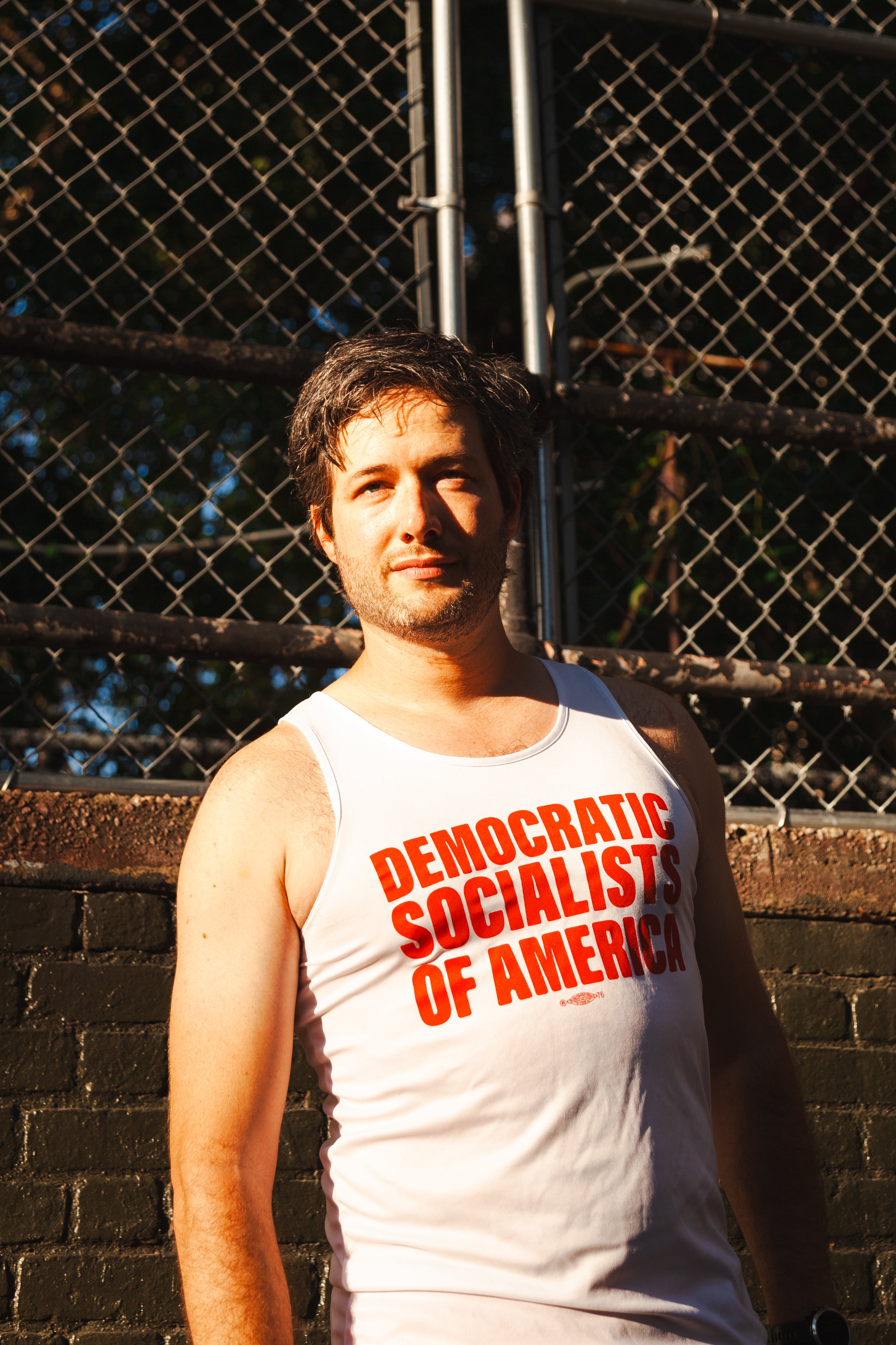 socialist wearing a DEMOCRATIC SOCIALISTS OF AMERICA tank top in a public park