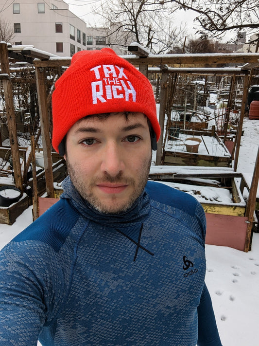 socialist wearing tax the rich beanie in a garden