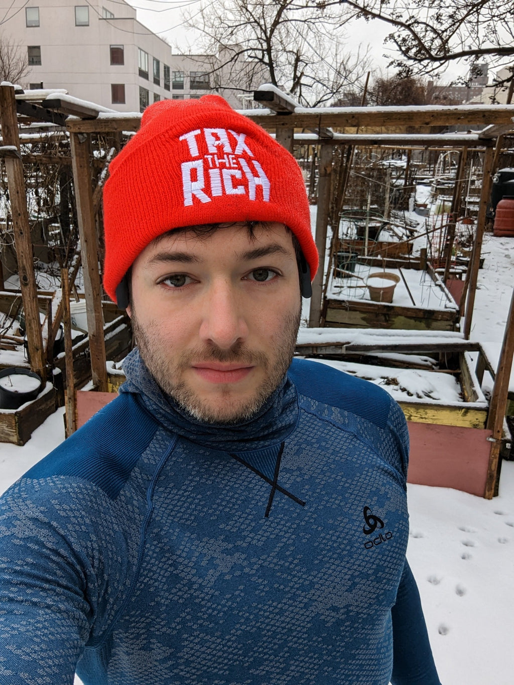 socialist wearing tax the rich beanie in a garden